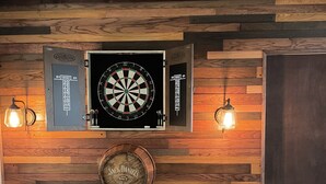 Eine Dartscheibe an einer Holzwand, darunter eine Uhr.