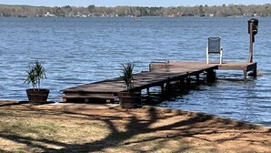 Eine Holzstele führt in einen See, mit einem Stuhl und Topfpflanzen darauf.