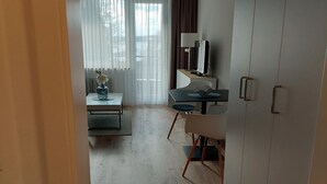 A modern living room with a dining area, a large wardrobe, and a window with curtains. - 2-room vacation apartment directly on Lake Constance with bathing area (Überlingen)