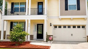 A two-story residential house with a front porch, a garage, and a small front yard.