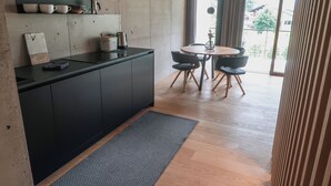Cozinha moderna com bancada preta, armários de madeira e área de refeições com mesa redonda e cadeiras.