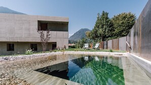 Um edifício moderno com piscina, rodeado por pedrinhas e plantas.