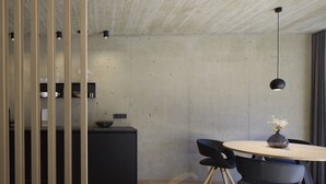 Uma zona de refeições moderna com uma mesa redonda, cadeiras pretas e um vaso com flores.