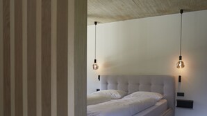 Quarto moderno com uma cama grande, duas mesas de cabeceira e luminárias pendentes.