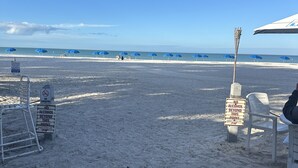 Ein Strand mit Sonnenschirmen, Liegestühlen und Schildern, die Rauchen und Alkoholkonsum ab einer bestimmten Stelle verbieten.