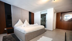 A modern bedroom with a large bed, a glass door leading to a balcony, and a wooden wardrobe. - Moderne Loft Wohnung Koblenz (Koblenz)