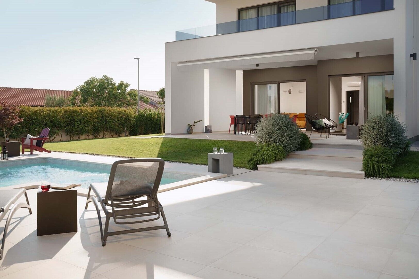 Una casa moderna con piscina, area relax esterna e prato curato.