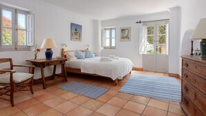 A bedroom with a bed, a wooden chair, a nightstand, a lamp, and a dresser. - The Old Mill: Pool, Sleeps 8, WiFi, 4 bed, views (Frigiliana)