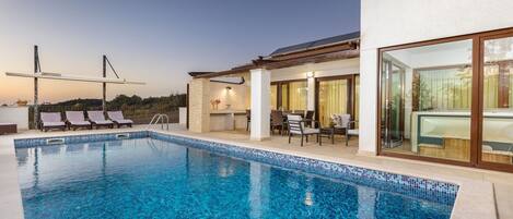 A swimming pool with lounge chairs and a covered patio area.