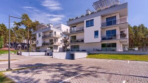Een modern meerlaags woongebouw met balkons, een geplaveid pad en een heldere lucht.