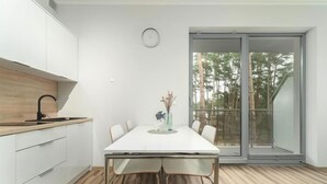 Een moderne keuken met een wit aanrecht, een zwarte kraan en een eethoek met een witte tafel en stoelen.