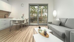 Een modern appartement met keuken, eethoek en balkon met uitzicht op bomen.