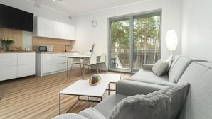 Een moderne woonruimte met een keuken, eethoek en een grote schuifpui naar een balkon.