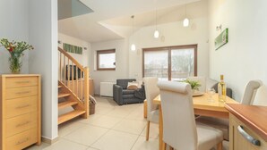 A modern dining area with a wooden table, chairs, and a staircase leading to another level. - Apartment in Rewal by Baltic Sea Beach (Rewal)