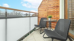 A balcony with two wicker chairs, a small round table, and a potted plant. - Apartment in Rewal by Baltic Sea Beach (Rewal)