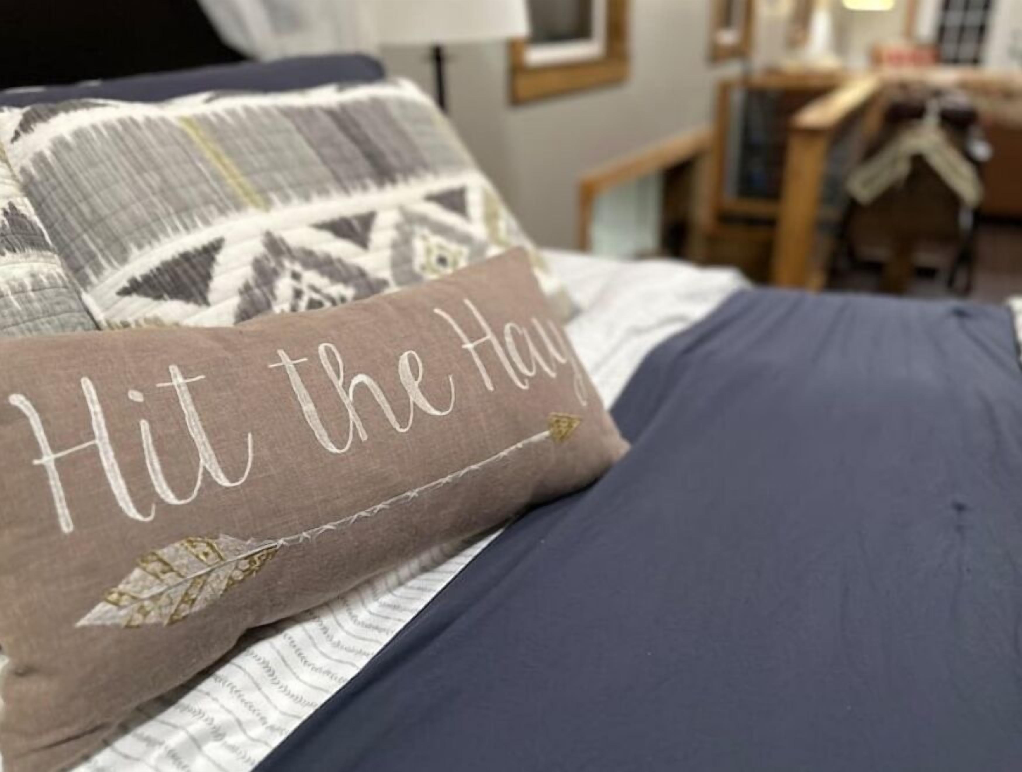 A bed with a pillow that reads "Hit the hay."