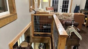 Una habitación estilo loft con escalera de madera, cama en entrepiso y un espacio pequeño y cerrado para zapatos.