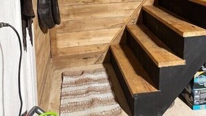 Una escalera de madera que lleva a un pequeño ventanal con marco blanco.