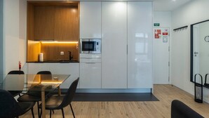 A modern kitchen with a microwave, a glass dining table, and black chairs.