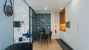A modern kitchen with a dining area, a clock, and a welcome sign on the wall.