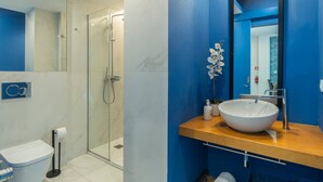 A modern bathroom with a glass-enclosed shower, a large white sink, and a blue accent wall.