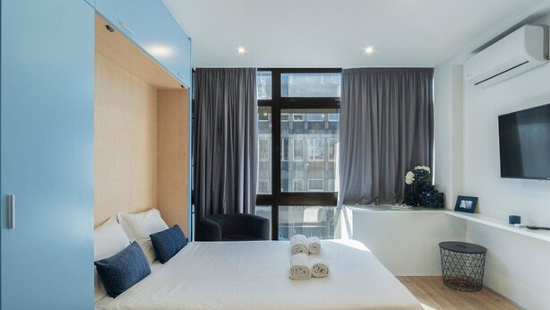 A modern hotel room with a large bed, a desk, and a TV.
