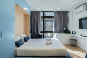 Ein modernes Hotelzimmer mit einem großen Bett, einem Schreibtisch und einem Fernseher.