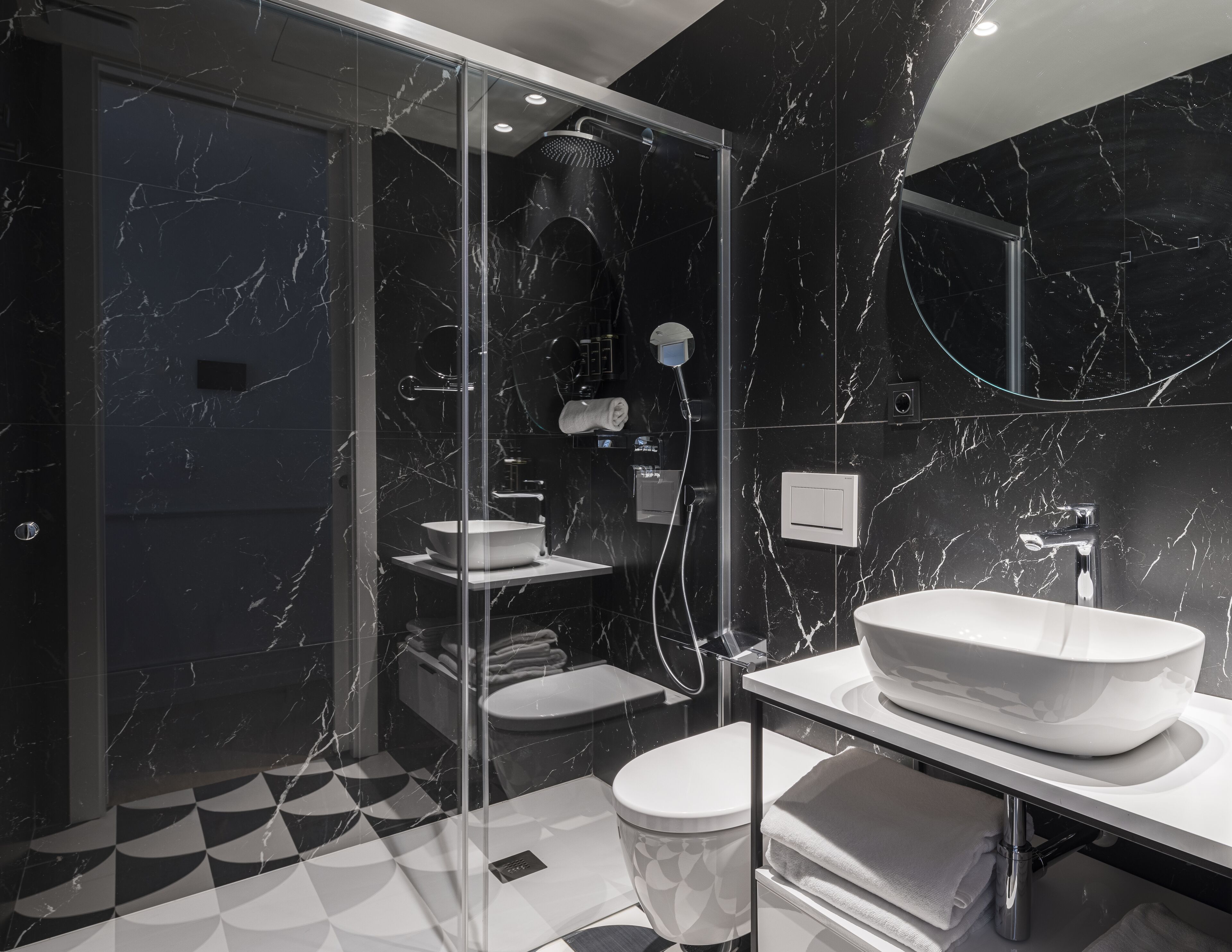 A modern bathroom with a glass-enclosed shower, a white sink, and a toilet.