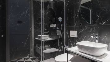 A modern bathroom with a glass-enclosed shower, a white sink, and a toilet.