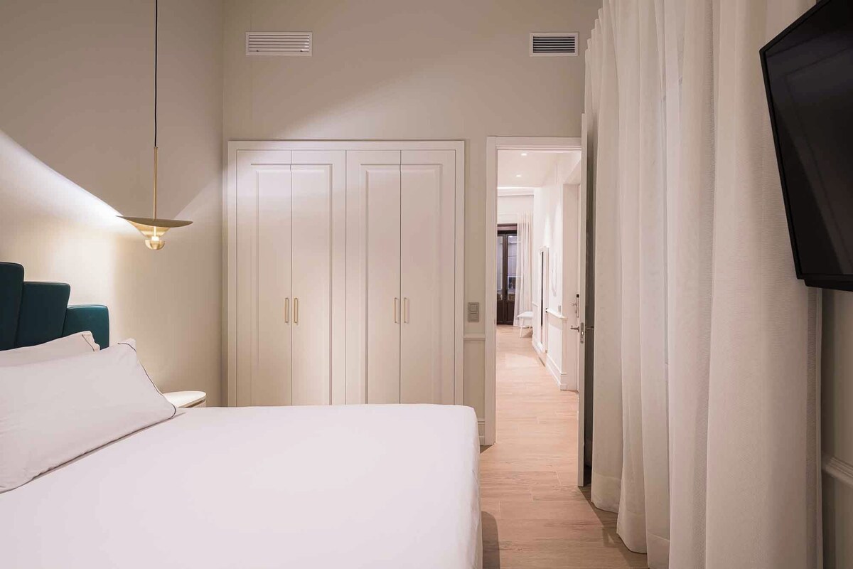 Quarto de hotel com cama, guarda-roupa, secretária e cadeira.