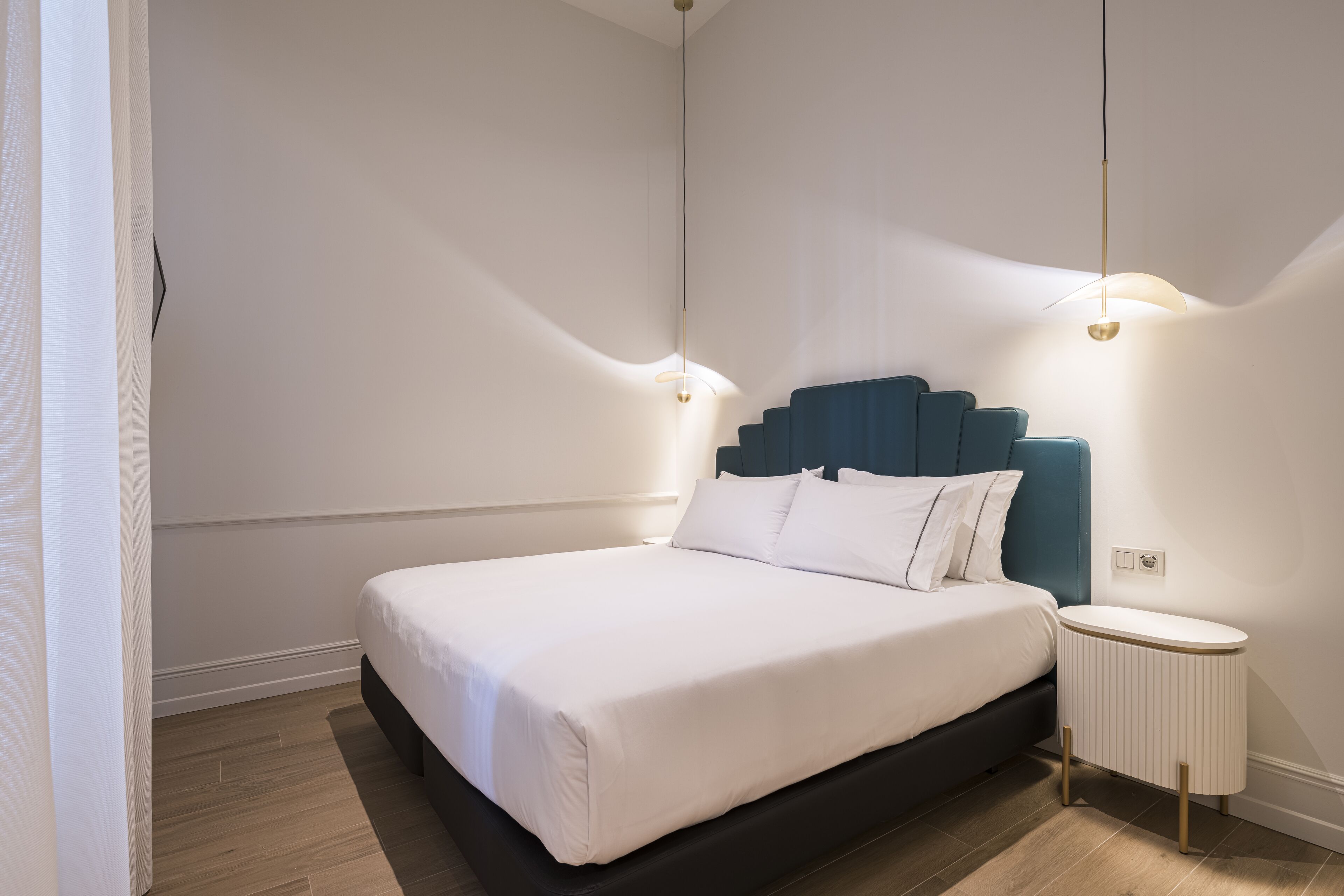 A modern bedroom with a large bed, a blue headboard, and two bedside lamps.