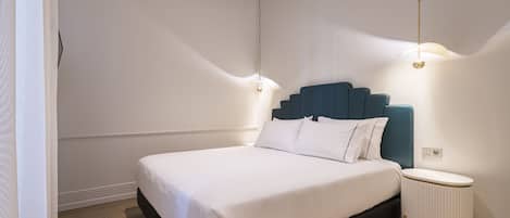 A modern bedroom with a large bed, a blue headboard, and two bedside lamps.