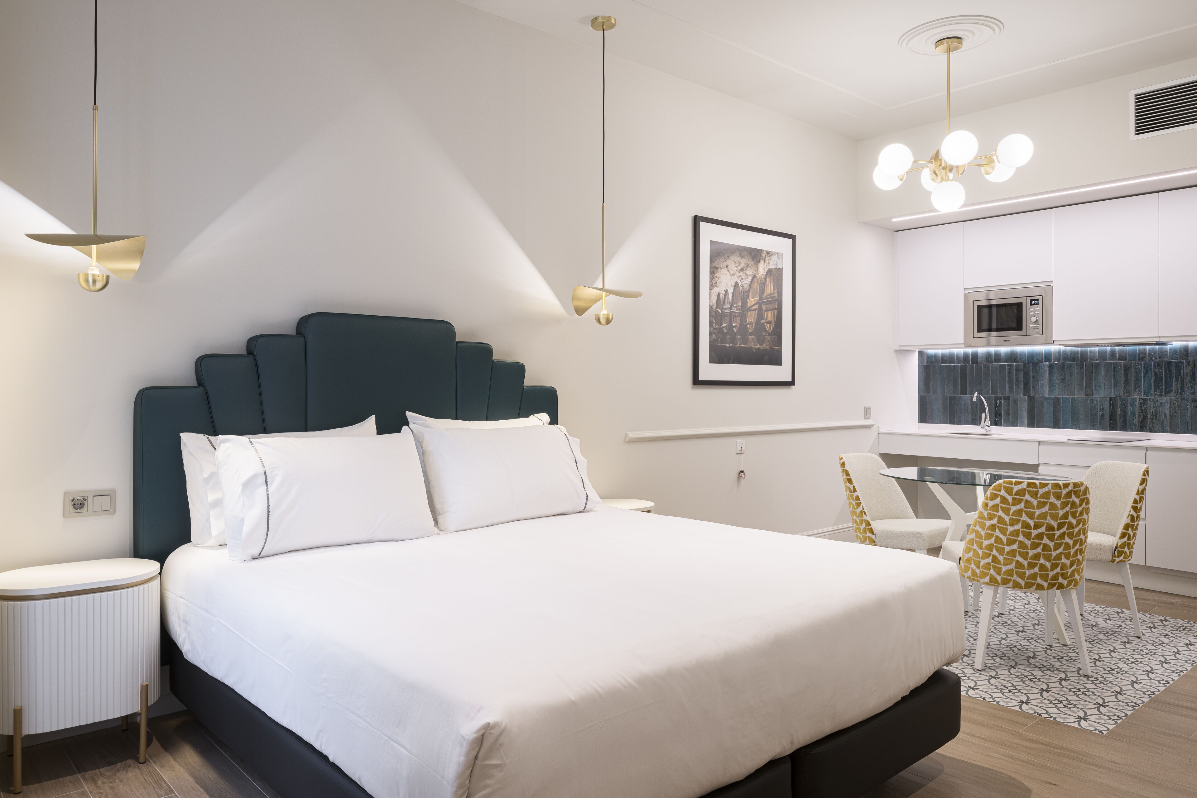 Una habitación de hotel moderna con una cama grande, un escritorio y una kitchenette.