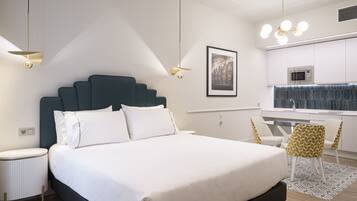 Una habitación de hotel moderna con una cama grande, un escritorio y una kitchenette.