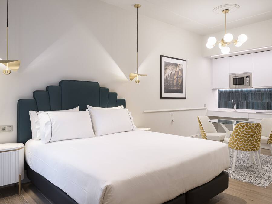 Una habitación de hotel moderna con una cama grande, un escritorio y una kitchenette.