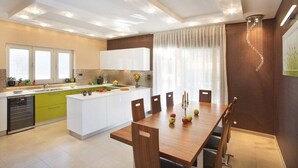 A modern kitchen with white cabinets, a green countertop, and a dining area with a wooden table and chairs. - Charming Villa Diora with a swimming pool and wellness area (Karojba)