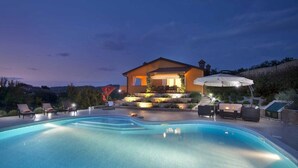 A house with a swimming pool, outdoor furniture, and a well-lit patio area. - Charming Villa Diora with a swimming pool and wellness area (Karojba)