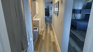 Un couloir étroit doté d’un plancher en bois, d’un ventilateur de plafond et d’un escalier menant à l’étage supérieur.
