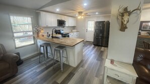 Une cuisine moderne dotée d’un îlot central, d’appareils électroménagers en acier inoxydable et d’un ventilateur de plafond.