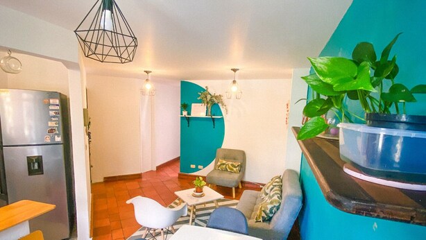 Un espace de vie compact comprenant un coin repas, une kitchenette et un mur d’accent bleu.