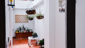 Un couloir intérieur agrémenté de jardinières suspendues, d’un banc et d’une table.