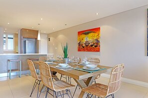 Un comedor moderno con una mesa de madera preparada para seis personas, rodeada de sillas de mimbre.