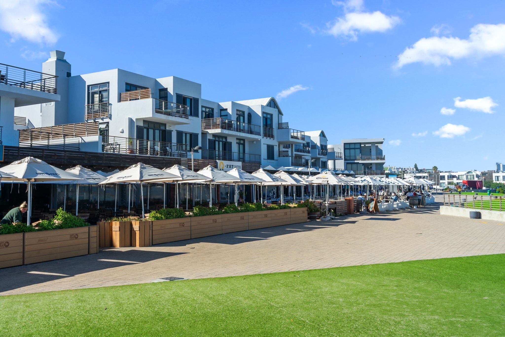 A modern hotel with multiple balconies, outdoor seating areas, and a paved walkway.