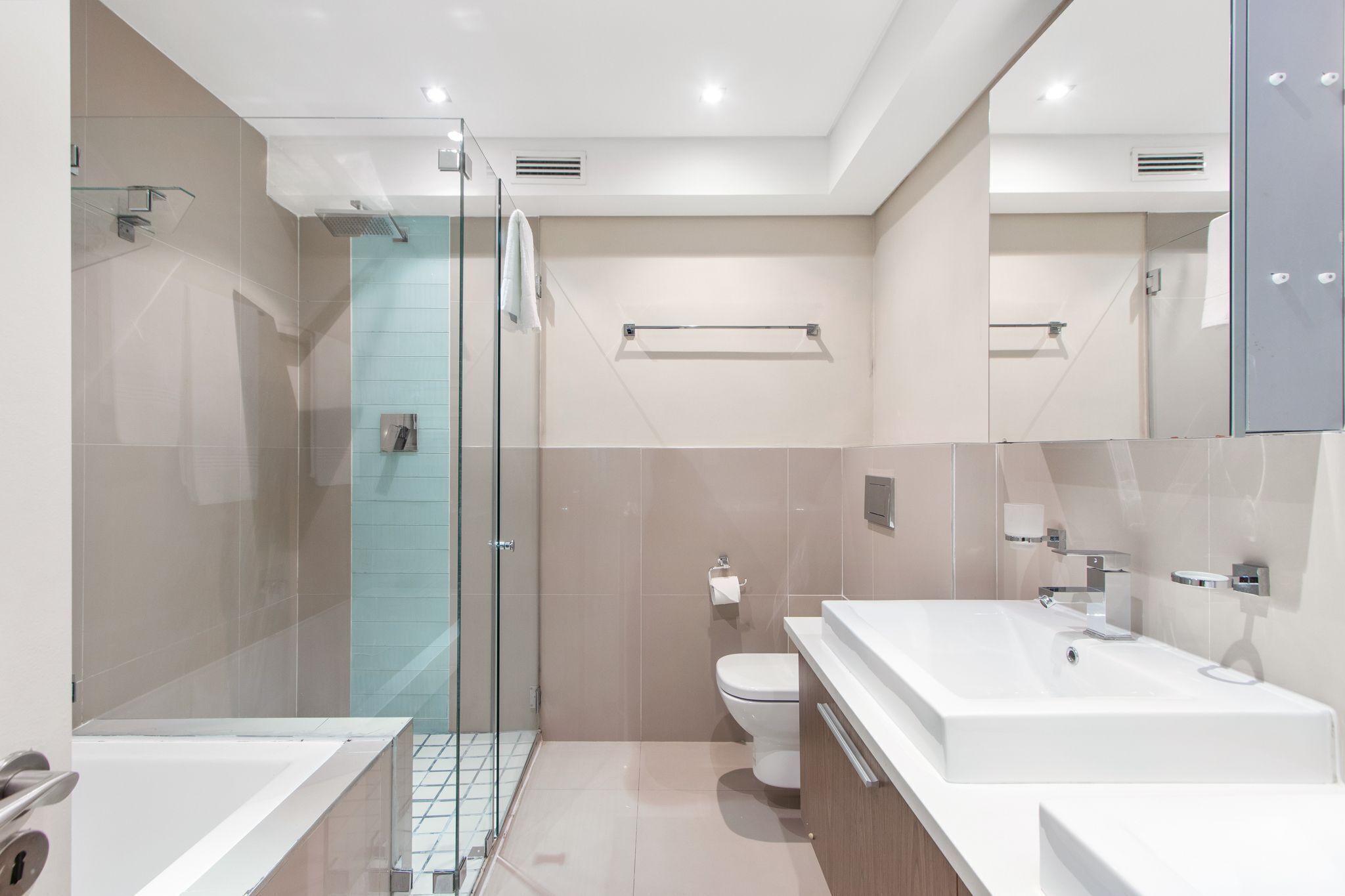 A modern bathroom with a glass shower enclosure, a white sink, and a toilet.