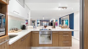 Une cuisine moderne dotée d’un îlot central, de meubles en bois et d’un four en acier inoxydable.