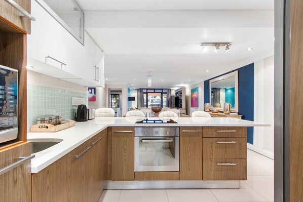A modern kitchen with a central island, wooden cabinets, and a stainless steel oven.