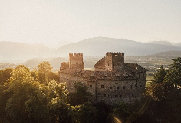 A historic stone castle with two prominent towers, surrounded by lush greenery and mountains in the background. - Schloss Freudenstein (Appiano Sulla Strada del Vino)