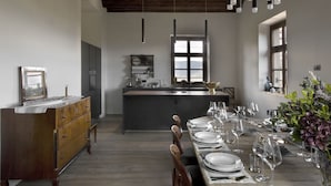 A modern kitchen with a central island, wooden cabinets, and a dining area set for a meal. - Schloss Freudenstein (Appiano Sulla Strada del Vino)
