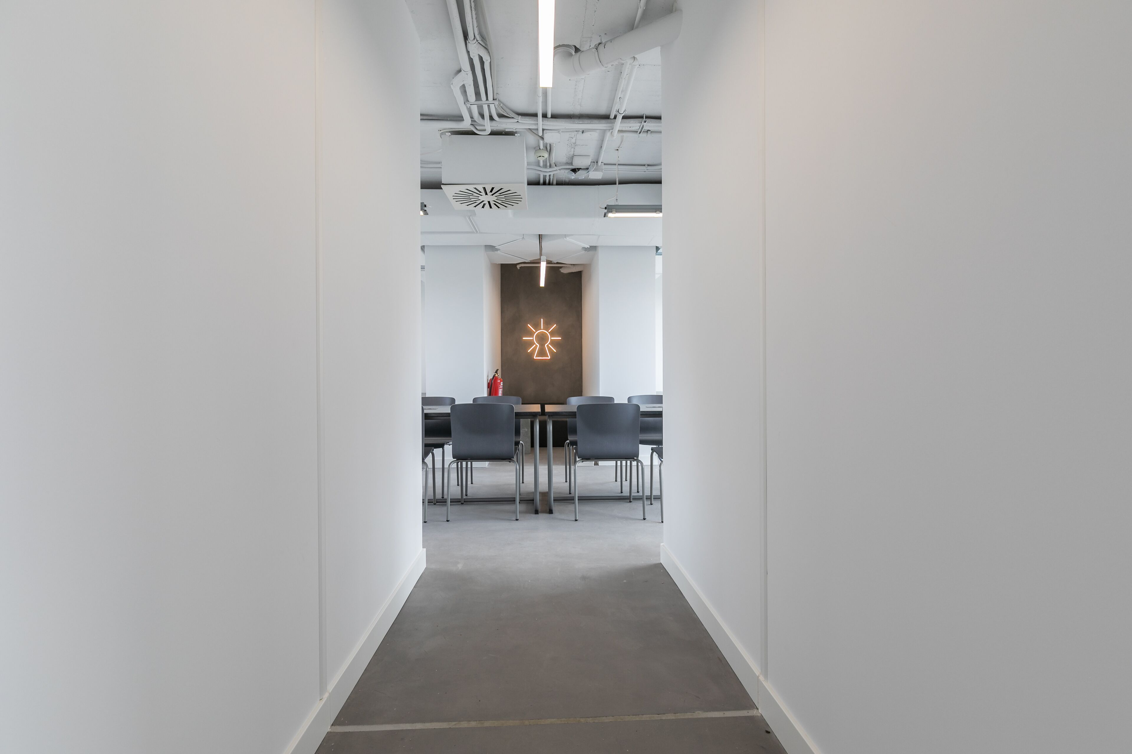 A modern conference room with a long table, chairs, and a unique wall decoration.