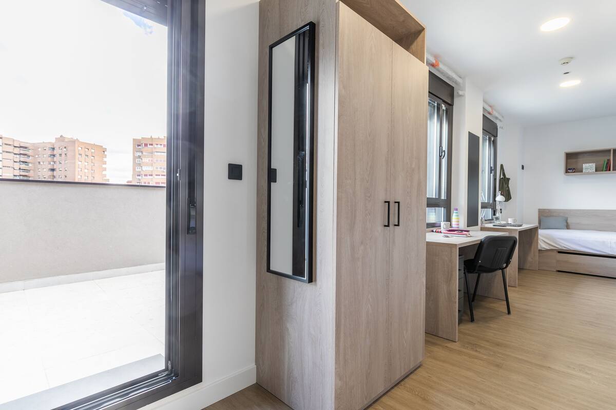 A modern bedroom with a large wardrobe, a desk, and a bed.